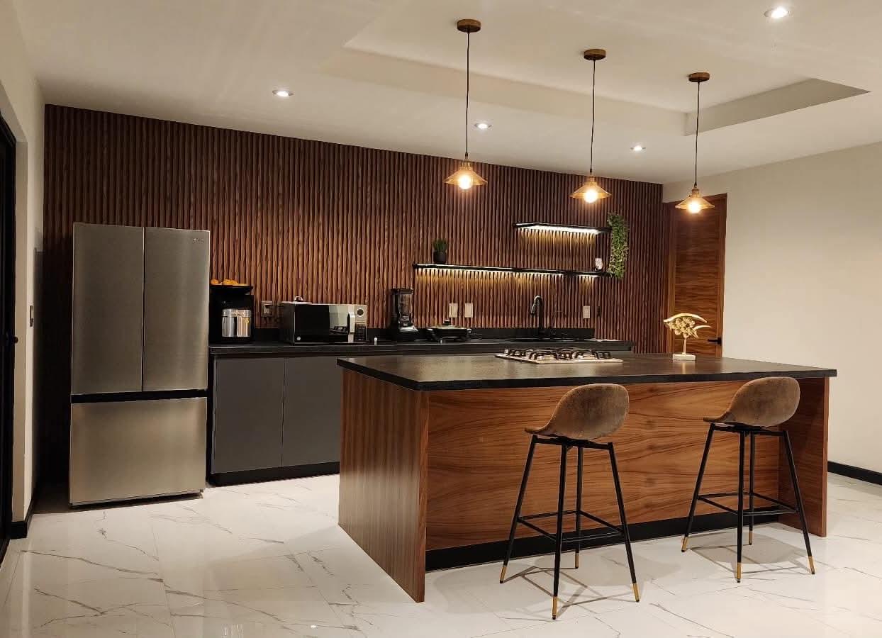 Cocina a la medida en nogal con isla e iluminación de autor